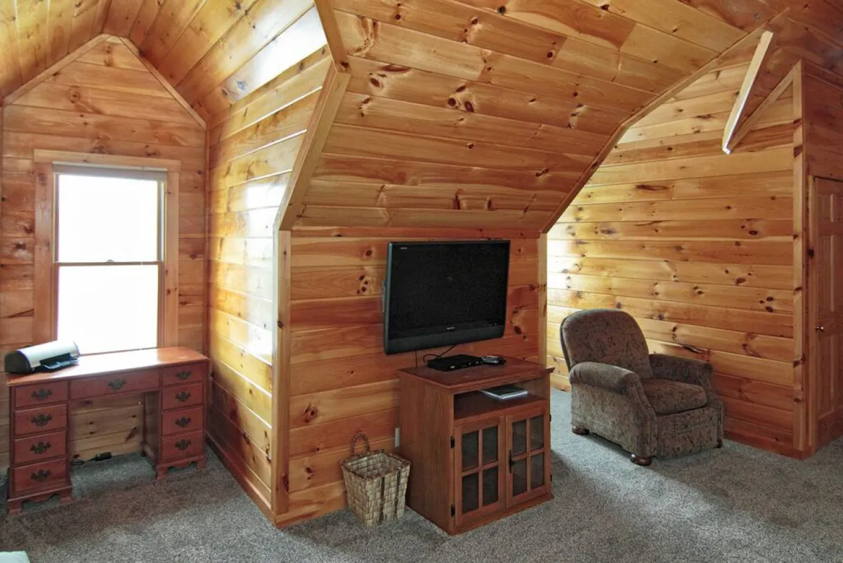 A comfortable lounge area featuring wooden walls and a plush chair set beside a window. The space invites relaxation, whether reading, watching TV, or enjoying views of the outdoors.