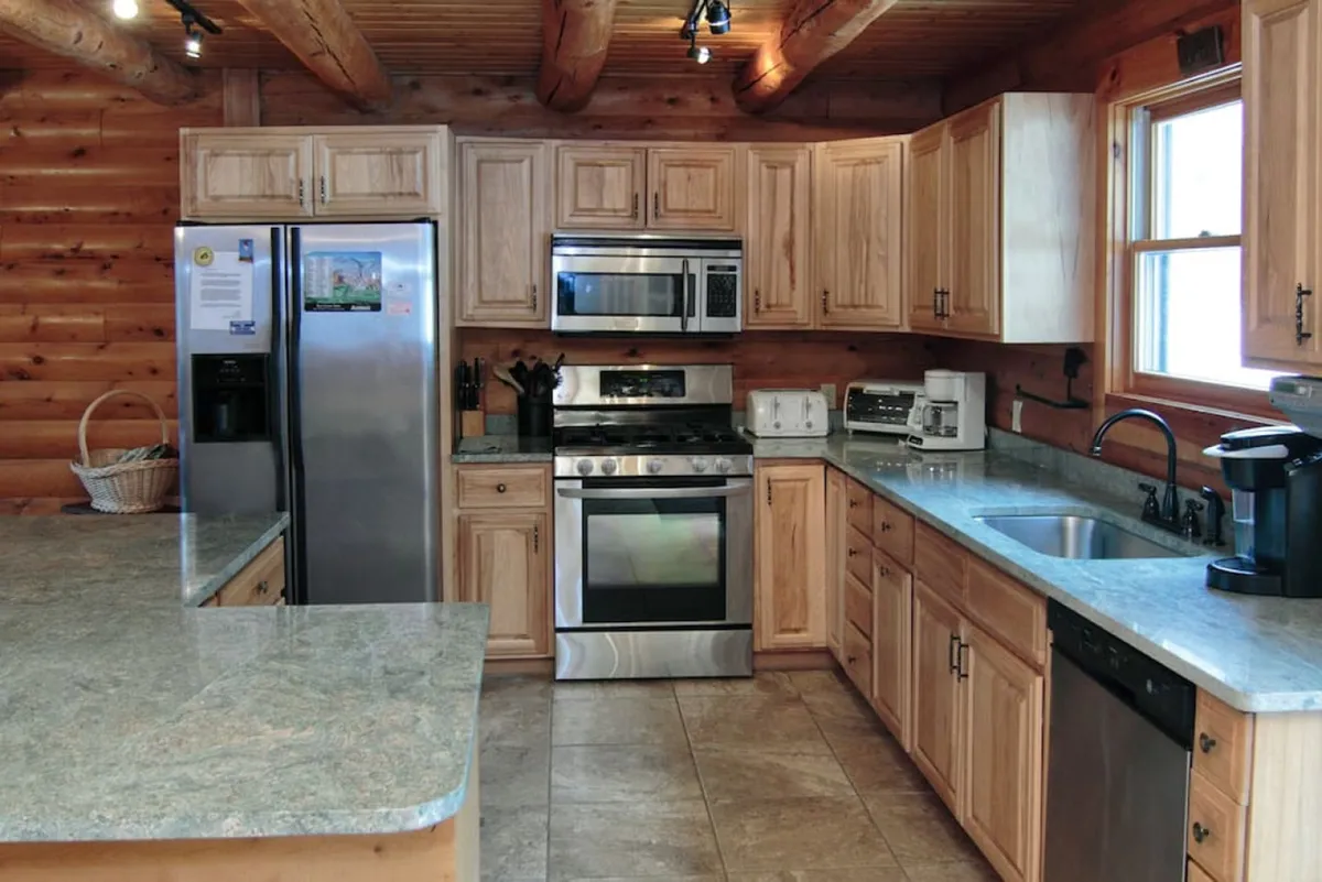 A well-equipped kitchen highlighted by stainless steel appliances, granite countertops, and wooden cabinetry. The layout encourages group cooking and social interaction, with ample space for meal preparation.