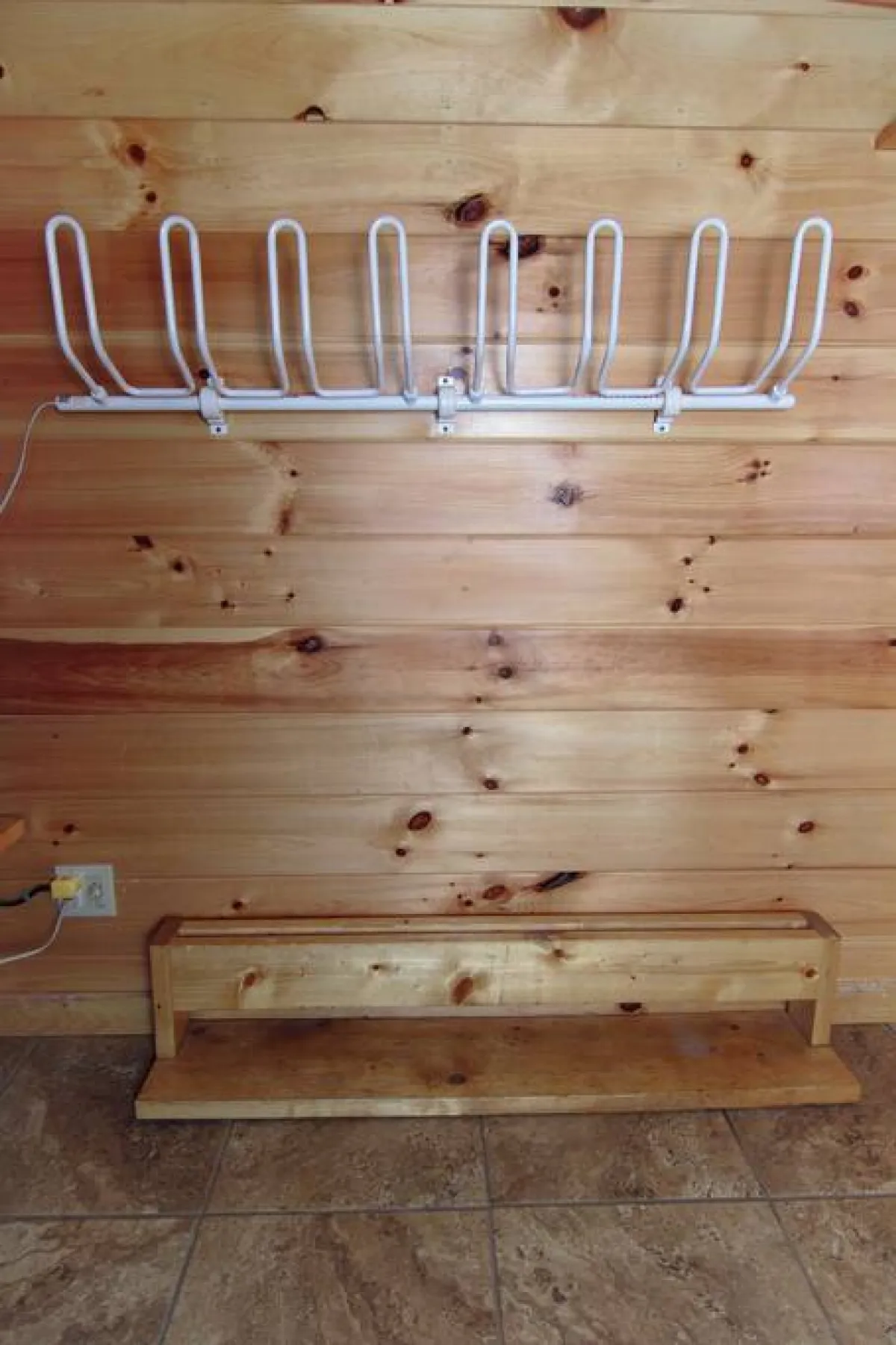This welcoming entryway features a wooden bench and coat rack against warm wooden walls, offering a practical spot to hang up gear and pause after a day outside. The cozy, inviting vibe reinforces the home’s role as a comfortable base for exploration.