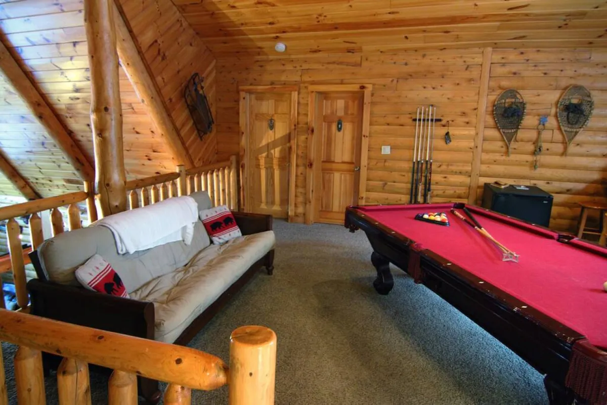 A playful interior shot with a pool table, plush sofa, rustic wooden accents, and decorative touches on the walls. The setting is casual yet stylish, designed for entertainment and relaxation.